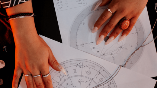 hands spread out over papers detailing astrological charts