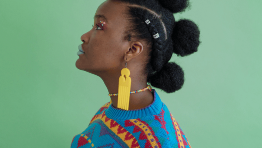 A black woman with a bright sweater stands with her side profile shown.