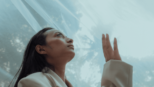 asian woman in a white blazer gazing up at the sky with sheer fabric hanging above