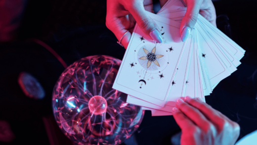 pair of hands holding out white tarot cards over a crystal ball