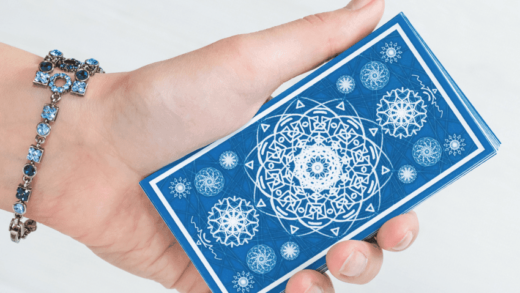 A hand holds a blue Tarot card.